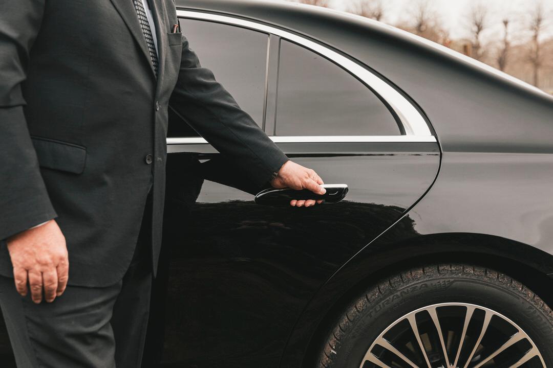 Driver holds the door of a Mercedes S-class open. 